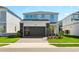 Two-story home with gray siding, dark gray garage door, and landscaped lawn at 16205 Saint Kitts Cir, Clermont, FL 34714