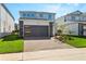 Two-story home with gray siding, dark gray garage door, and landscaped lawn at 16205 Saint Kitts Cir, Clermont, FL 34714