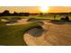 Scenic golf course featuring a lush green fairway, sand traps, and a golf cart, set against a backdrop of a vibrant sunset at 16800 Bolsena Dr, Montverde, FL 34756
