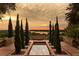 Relaxing outdoor space with a reflecting pool, cypress trees, and a bench overlooking a serene landscape and sunset at 16800 Bolsena Dr, Montverde, FL 34756