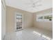 Bright bedroom features white tile flooring, ceiling fan, and a door leading to the outside at 213 Oakland Ave, Sanford, FL 32773