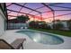 Tranquil pool at sunset with screened enclosure, patio furniture, and lounge chairs at 2610 Autumn Creek Cir, Kissimmee, FL 34747