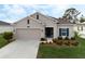 Beige house with blue shutters, two-car garage, and neatly landscaped yard at 4530 Tahoe Cir, Clermont, FL 34714