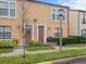 Tan two-story townhome with a red door, landscaping, and a bench at 715 Siena Palm Dr, Celebration, FL 34747