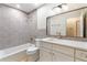 Updated bathroom with gray tile, a white vanity, and gold fixtures at 7884 Broken Arrow Trl, Winter Park, FL 32792