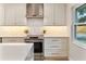 Close up of the kitchen with the range hood, stainless steel range, custom drawers, and quartz countertop at 7884 Broken Arrow Trl, Winter Park, FL 32792