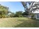 Large backyard with grassy area, mature trees, and a wooden fence at 913 Carlson Dr, Orlando, FL 32804