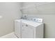 Bright laundry room features a white washer and dryer plus additional shelving for storage space at 1040 Sadie Ridge Rd, Clermont, FL 34715