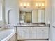 Bathroom featuring dual sinks, a granite countertop, a soaking tub, an archway detail, and a separate walk-in shower at 1040 Sadie Ridge Rd, Clermont, FL 34715