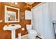 Bathroom with pedestal sink, white toilet, and terracotta walls at 1107 Lantana Dr, Eustis, FL 32726