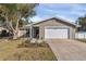 Cute ranch home with a white garage door and landscaped lawn at 1107 Lantana Dr, Eustis, FL 32726