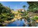 Scenic pond with rock waterfalls and landscaping in front of home with a view of the roof and balcony at 11148 Lane Park Rd, Tavares, FL 32778