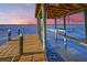 Covered dock with a boat lift at sunset, calm water view at 118 River Ln, Ormond Beach, FL 32176