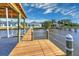 Long wooden dock stretching to a covered boathouse on a sunny day at 118 River Ln, Ormond Beach, FL 32176