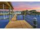 Long wooden dock stretching to a covered boathouse at sunset at 118 River Ln, Ormond Beach, FL 32176