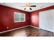 Red bedroom featuring hardwood flooring, a ceiling fan, and a window at 13132 Coldwater Loop, Clermont, FL 34711