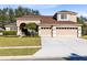 Two-story home with tan stucco, a three-car garage, and well maintained landscaping at 13132 Coldwater Loop, Clermont, FL 34711