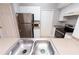 Kitchen with stainless steel appliances, double sink, white cabinets, and tiled floor at 2302 Midtown Ter # 1228, Orlando, FL 32839