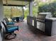 Covered outdoor kitchen with built-in grill, dining table, and ample seating at 2530 Domenico Paul Way, Orlando, FL 32810