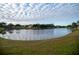 Calm lake view with lush green grass and cloudy sky at 2612 Keswick Ct, Kissimmee, FL 34744