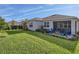 Spacious backyard featuring a screened patio with outdoor seating, well-manicured green grass, and lush landscaping at 2812 Ruby Rose Ln, St Cloud, FL 34771