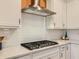 Close-up of the modern gas range, vent hood, and white subway tile backsplash in the kitchen at 2812 Ruby Rose Ln, St Cloud, FL 34771