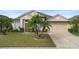 Tan one-story house with palm trees, two-car garage, and landscaped lawn at 2920 River Birch Dr, Kissimmee, FL 34741