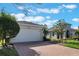 White two-car garage with paver driveway and landscaping at 560 Presido Park Pl, Kissimmee, FL 34759