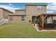 Spacious backyard with grassy lawn and a two-story house with pergola at 648 Cortona Dr, Orlando, FL 32828