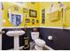 Stylish bathroom with yellow and black walls, pedestal sink, and toilet at 648 Cortona Dr, Orlando, FL 32828