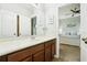 Clean bathroom with wood cabinets, a large mirror, and a view of a bedroom at 648 Cortona Dr, Orlando, FL 32828
