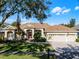 One-story house with a three car garage, red front door, and lush landscaping at 8231 Lynch Dr, Orlando, FL 32835