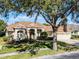 House exterior showcasing a three-car garage and a large oak tree at 8231 Lynch Dr, Orlando, FL 32835