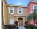 Two-story townhome with tan and pink exterior, landscaping, and walkway at 8513 Crystal Cove Loop, Kissimmee, FL 34747