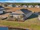 Aerial view showcasing a house with a screened lanai and lake view at 8575 Hempstead Way, Mount Dora, FL 32757