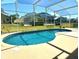 Kidney shaped swimming pool with a screened enclosure at 1708 Clubhouse Cv, Haines City, FL 33844