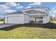 Well-lit home's rear exterior features an attached two-car garage, covered porch, and sliding glass doors at 2655 Trafalgar Blvd, Kissimmee, FL 34758