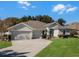 Single-story house with a two-car garage and lush green landscaping at 381 Skyview Pl, Chuluota, FL 32766