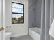 Bright bathroom features a shower over tub, gray tile, and a window showcasing neighborhood view at 809 Maxwell St, Orlando, FL 32804