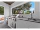Outdoor kitchen features stainless steel appliances, granite countertops, and picturesque views of the backyard and trees at 809 Maxwell St, Orlando, FL 32804