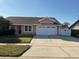 Tan house with a two-car garage and a fenced backyard at 1938 Gamboge Dr, Orlando, FL 32822