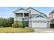 Two-story house with gray siding, teal accents, and a two-car garage at 2119 Victoria Dr, Davenport, FL 33837