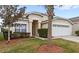 Tan one-story house with a two-car garage and palm trees at 2220 Wyndham Palms Way, Kissimmee, FL 34747