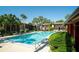 Bright, sunny view of community pool surrounded by tropical palm trees, with condos in the background at 734 E Michigan St # 113, Orlando, FL 32806