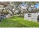 Backyard with large shed, well-maintained lawn, trees, and covered patio at 8836 Ava Lake Dr, Orlando, FL 32810