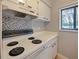 Kitchen features white cabinets, mosaic backsplash, and an electric range at 127 Springwood Cir # A, Longwood, FL 32750