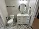 Cozy bathroom featuring a circular mirror, white vanity with marble top, and patterned tile flooring at 205 Hazard St, Orlando, FL 32804