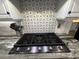 Close up of kitchen cooktop and patterned backsplash with granite counters at 205 Hazard St, Orlando, FL 32804