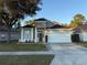 Tan house with a red door, two-car garage, and neatly landscaped yard at 371 Lexingdale Dr, Orlando, FL 32828