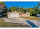 Tan single story house with a red door, attached garage, and a large yard at 5711 Bolling Dr, Orlando, FL 32808